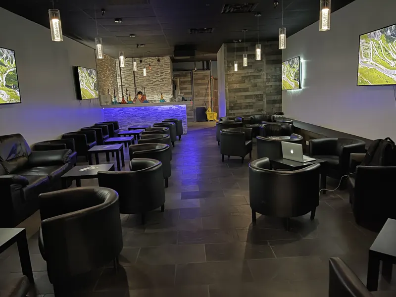 The back lounge with black leather club chairs, stone walls and violet light