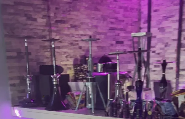 Modern steel hookahs lined up on the stone shelf under violet light