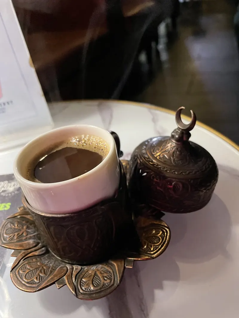 Turkish coffee in an engraved copper holder with a matching lidded sugar pot on a marble table